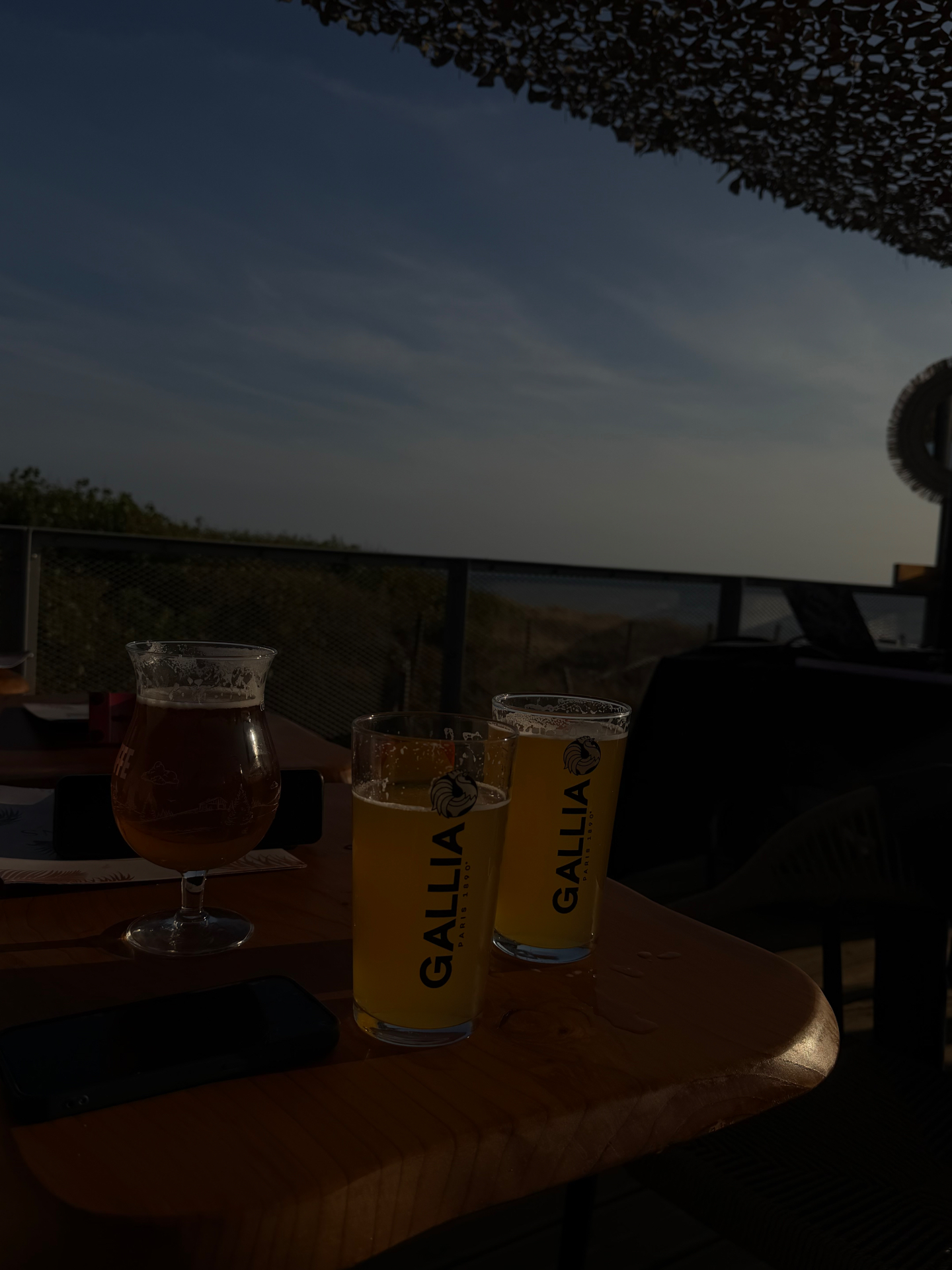 Bières Gallia fraîches sur une table en bois au coucher de soleil