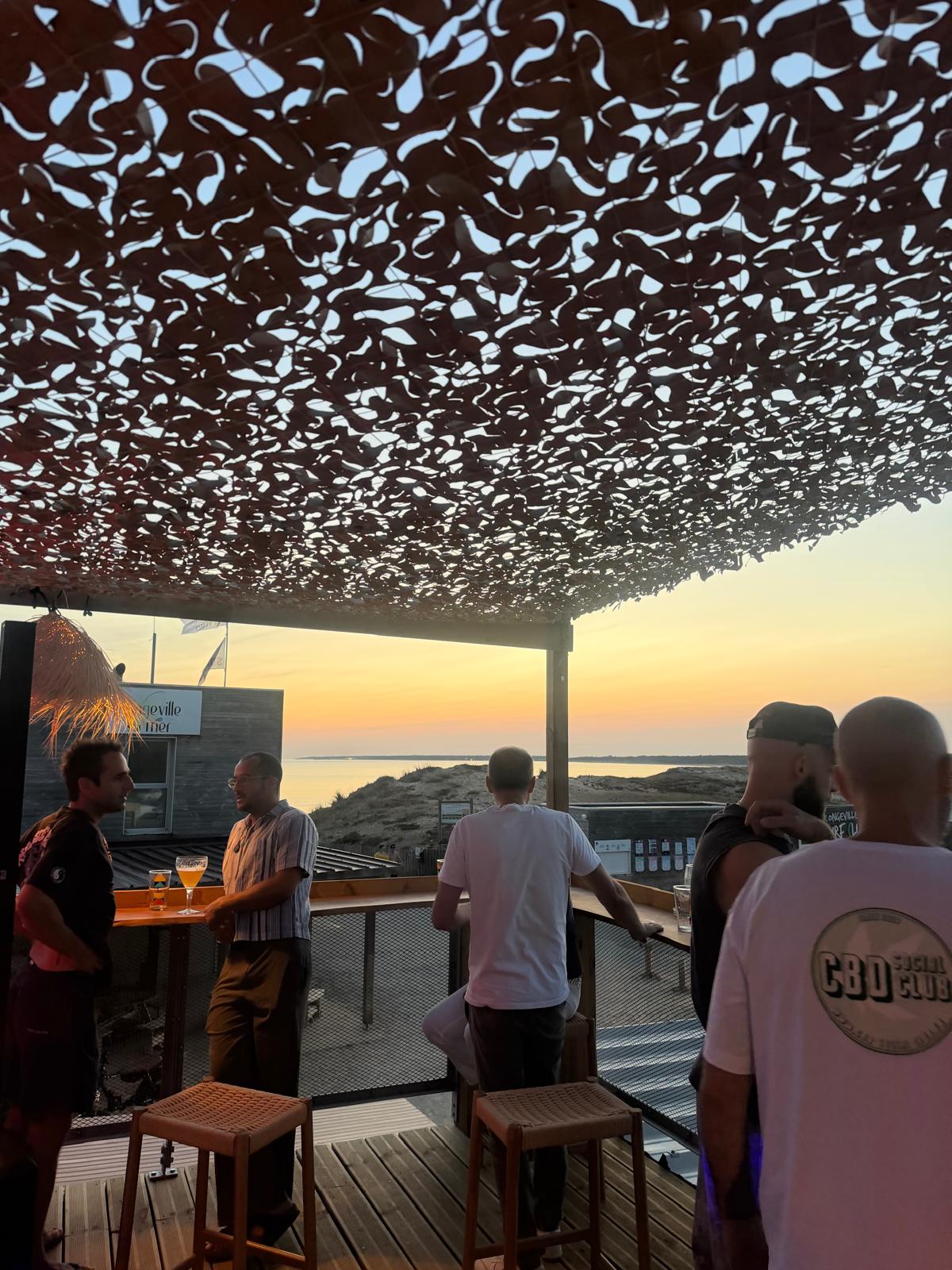 Silhouettes accoudées au comptoir face au coucher de soleil sur l'océan